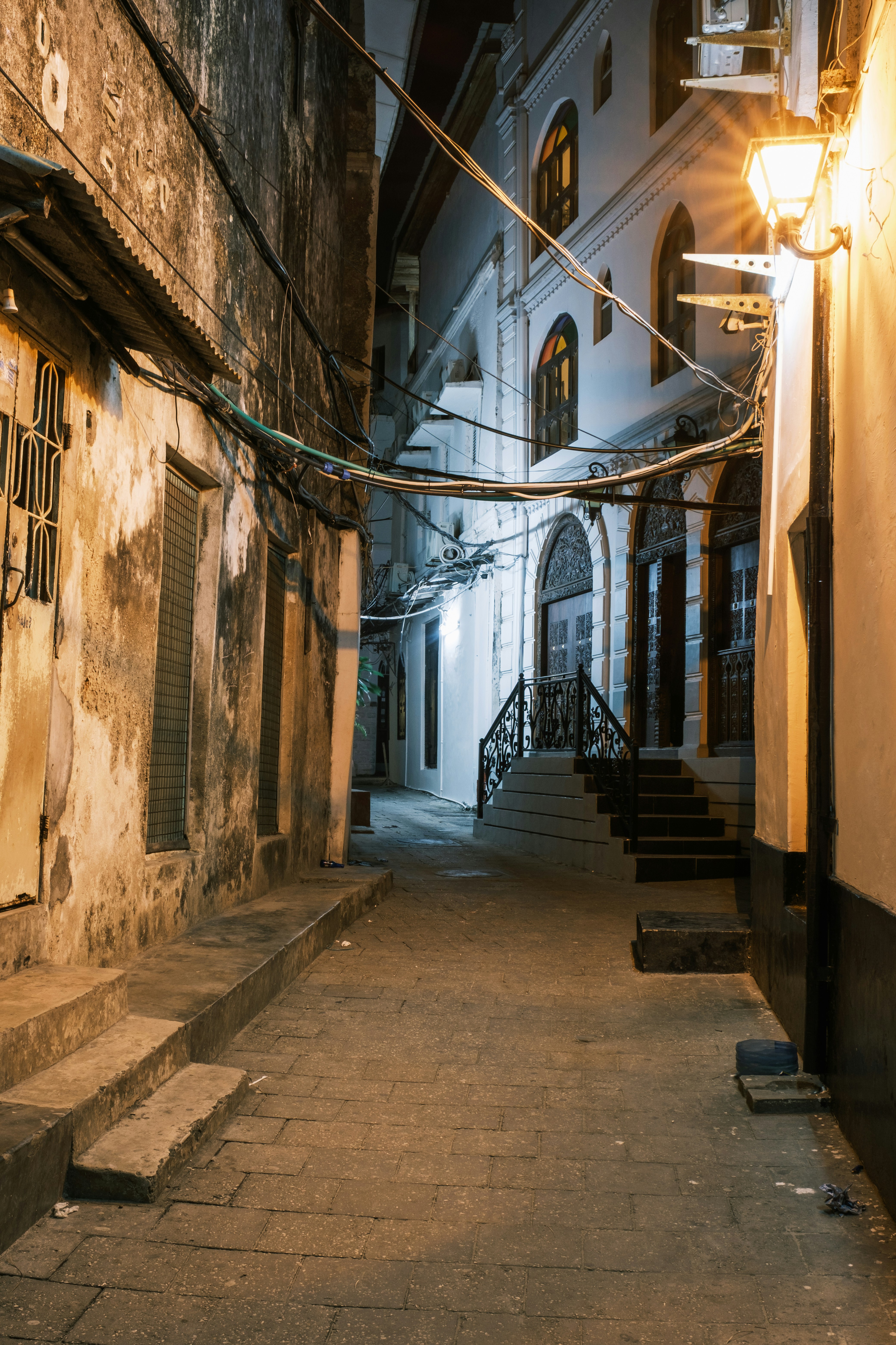 Narrow historic Stone Town street at night with old buildings and warm lights
